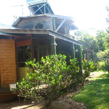 The image depicts a charming wooden house with a covered porch, surrounded by lush greenery and a vibrant garden, exuding a sense of serenity and natural beauty.